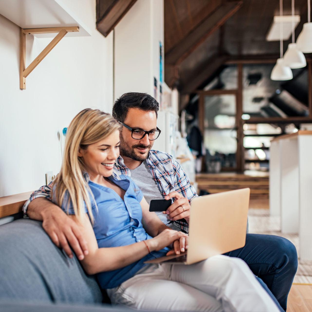 a couple sits on their couch researching the benefits of debt consolidation for high-interest credit card debt