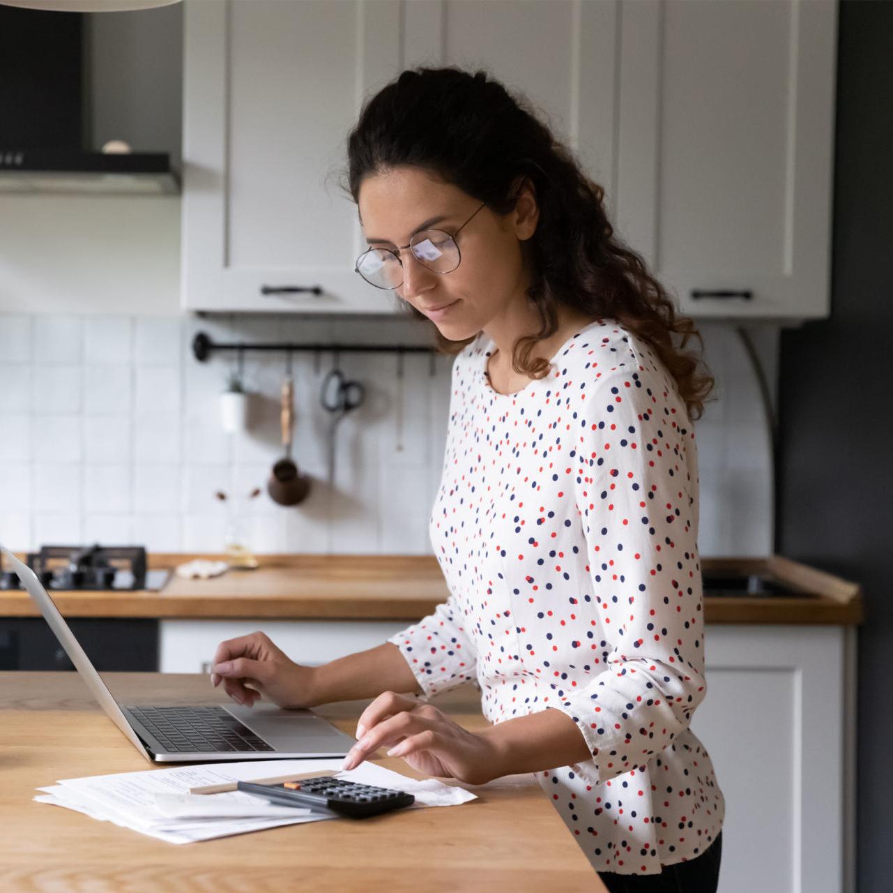 a woman calculates upcoming expenses and decides to apply for a personal loan vs. a personal line of credit in order to pay for them