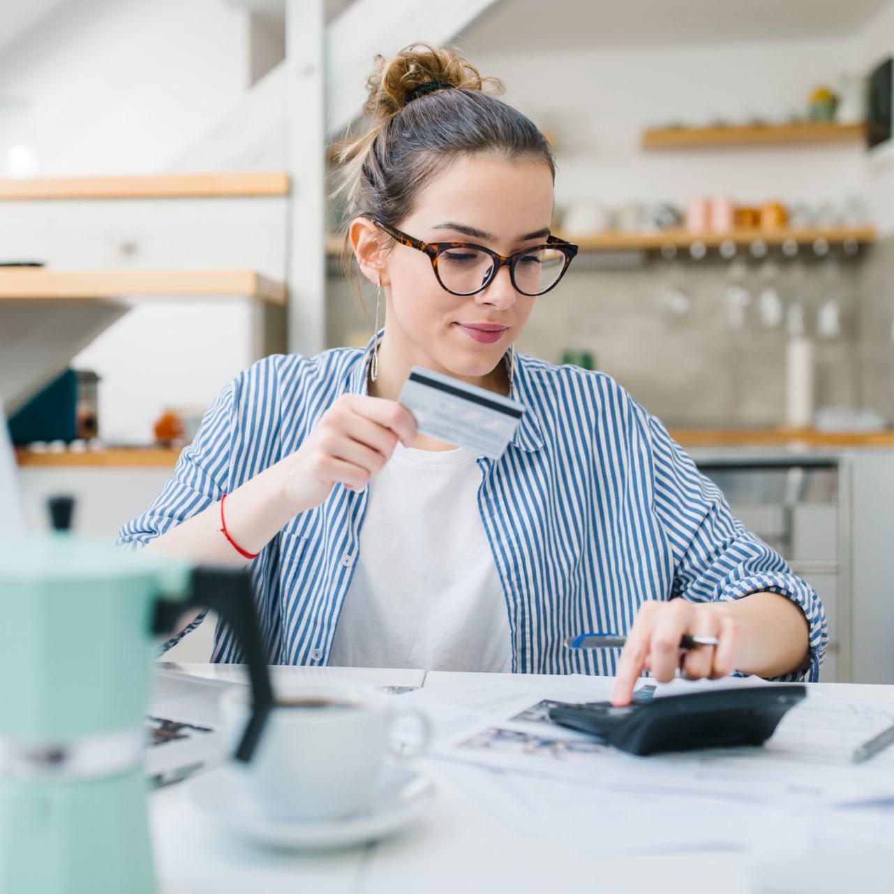 A young woman calculates her credit card payments and considers consolidating credit card debt.